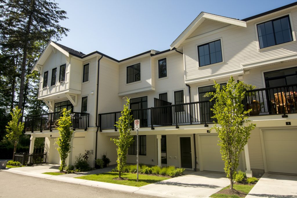A white townhome with black gutters.